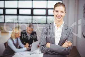 Businesswoman smiling while business people sitting in backgroun