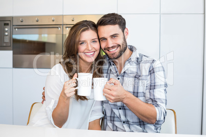 Happy couple drinking coffee by table