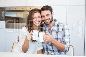 Happy couple drinking coffee by table
