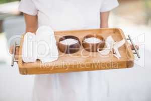 Female masseur holding tray with spa therapy products