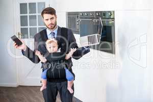 Businessman holding cellphone and laptop while carrying daughter
