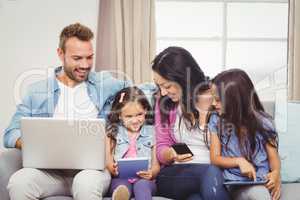 Family using modern technologies on sofa