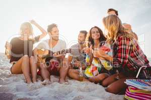 Happy friends having fun while sitting on sand