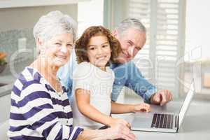 Portrait of happy girl with grandparents using laptop