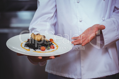Proud chef holding a plate of squid ink spaghetti