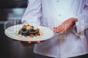 Proud chef holding a plate of squid ink spaghetti