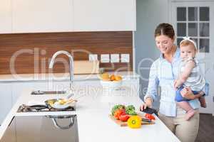 Woman carrying daughter by kitchen counter