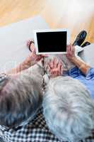 Senior couple using a digital tablet on sofa