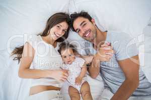 High angle view of happy family lying on bed