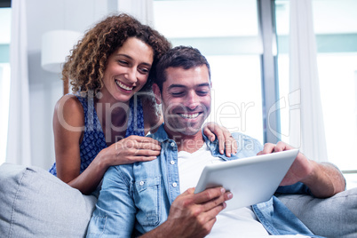 Young couple using a digital tablet on sofa