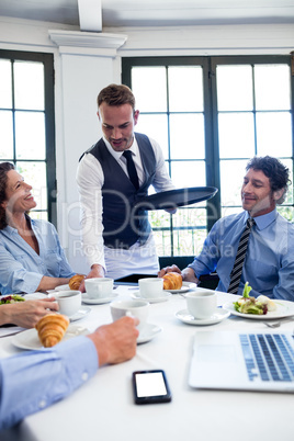 Waiter serving coffee to business people