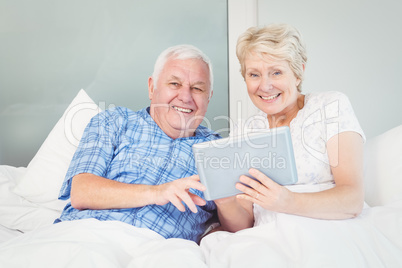 Portrait of senior couple using tablet on bed