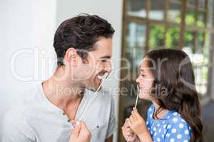 Smiling father and daughter with artificial mustache