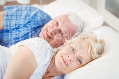 Portrait of happy senior couple resting on bed