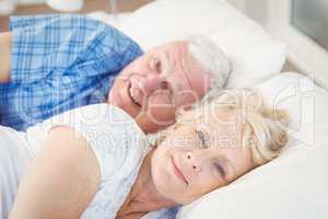 Portrait of happy senior couple resting on bed