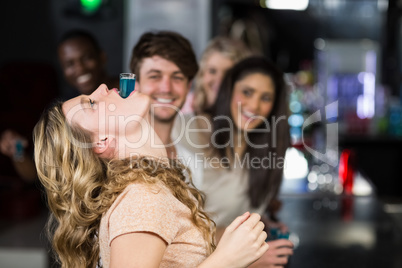 Blonde woman with a shot in her mouth