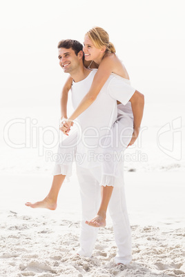 Man giving a piggy back to woman on the beach