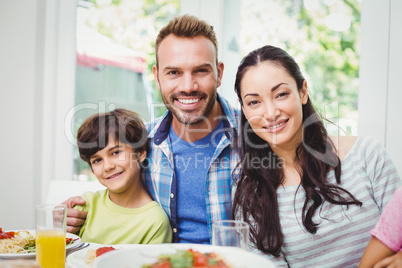 Portrait of smiling parents and son at dining table