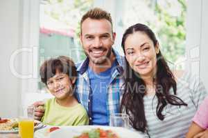 Portrait of smiling parents and son at dining table
