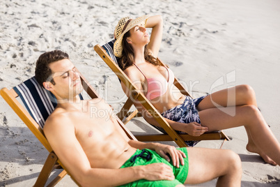 Young couple relaxing on armchair on the beach