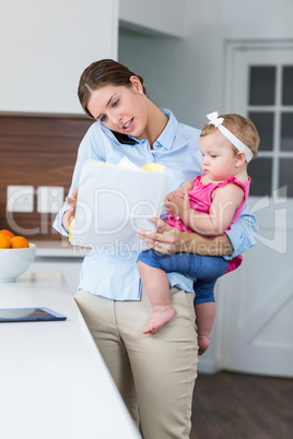 Woman looking in documents while carrying baby girl
