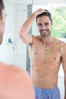 Shirtless man smiling while looking in mirror