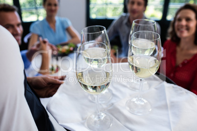 Waiter serving wine to friends in restaurant