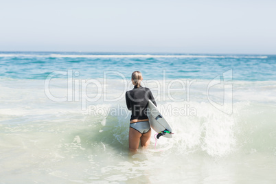 Woman with surfboard walking towards sea