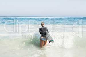 Woman with surfboard walking towards sea