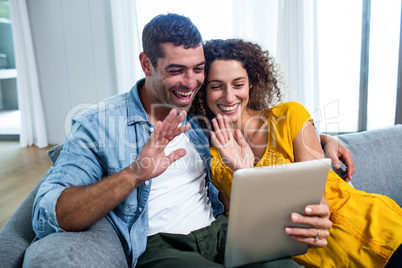 Happy couple using a digital tablet on sofa