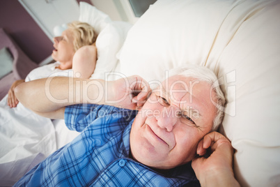 Portrait of man covering ears from snoring wife