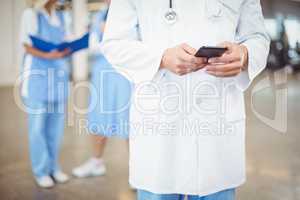 Midsection of doctor using mobile phone