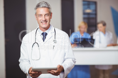 Portrait of smiling senior doctor holding digital tablet