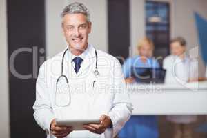 Portrait of smiling senior doctor holding digital tablet