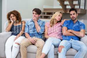 Upset young friends on sofa in living room