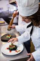 Female chef garnishing meal on counter