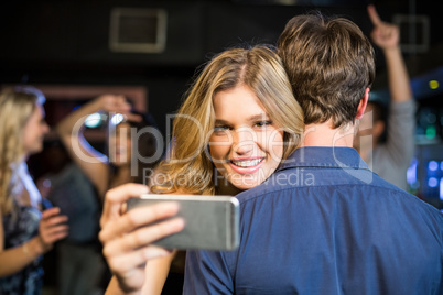 Woman using smartphone while hugging boyfriend