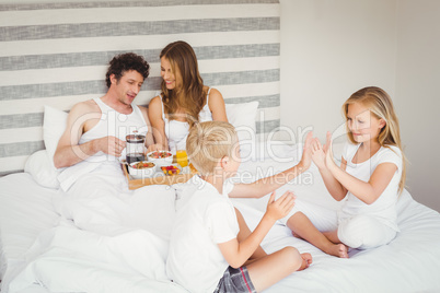 Playful siblings with parents on bed