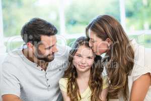 Mother kissing daughter while father watching them