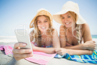 Two woman lying on the beach and looking at mobile phone