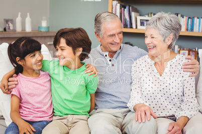 Happy grandchildren with grandparents on sofa at home