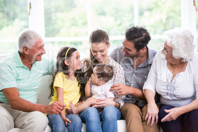 Smiling family with baby while sitting on sofa