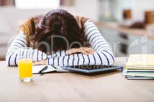 Woman napping with head by digital tablet and books
