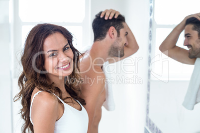 Portrait of woman smiling while man looking in mirror