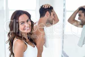 Portrait of woman smiling while man looking in mirror