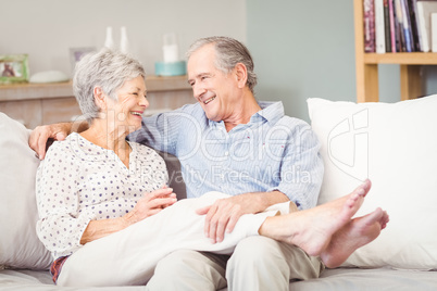 Happy senior couple sitting on sofa in living room