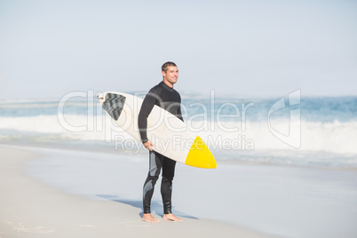 Surfer holding a surfboard on the beach
