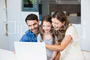 Family laughing while looking at laptop