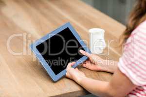 Woman using digital tablet by table at home