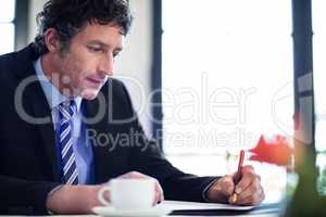 Businessman writing notes in restaurant